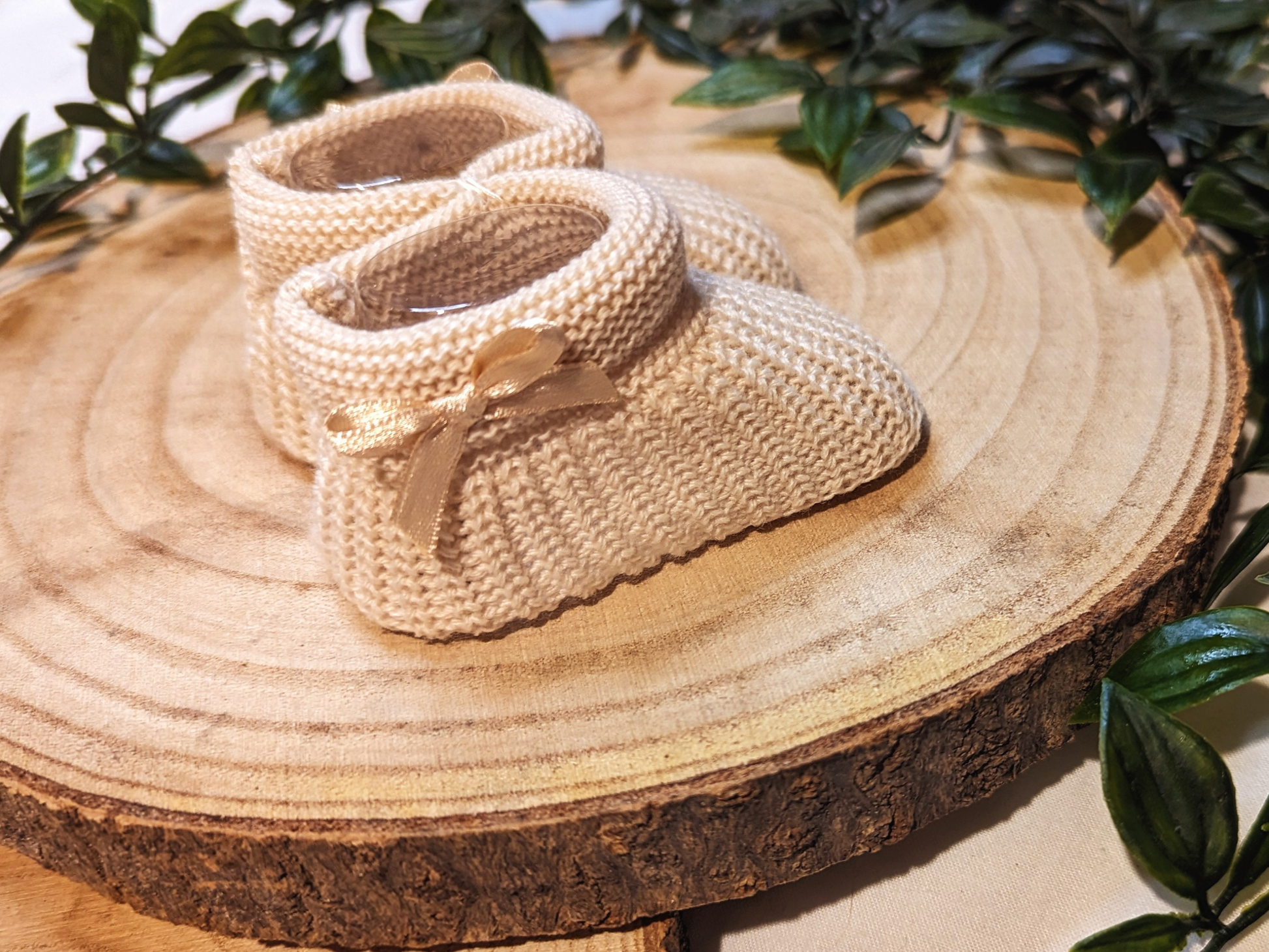 Unisex Newborn Clothes - Baby booties with a biscuit coloured knitted design, featuring a small bow on the side. (Side Angle)
