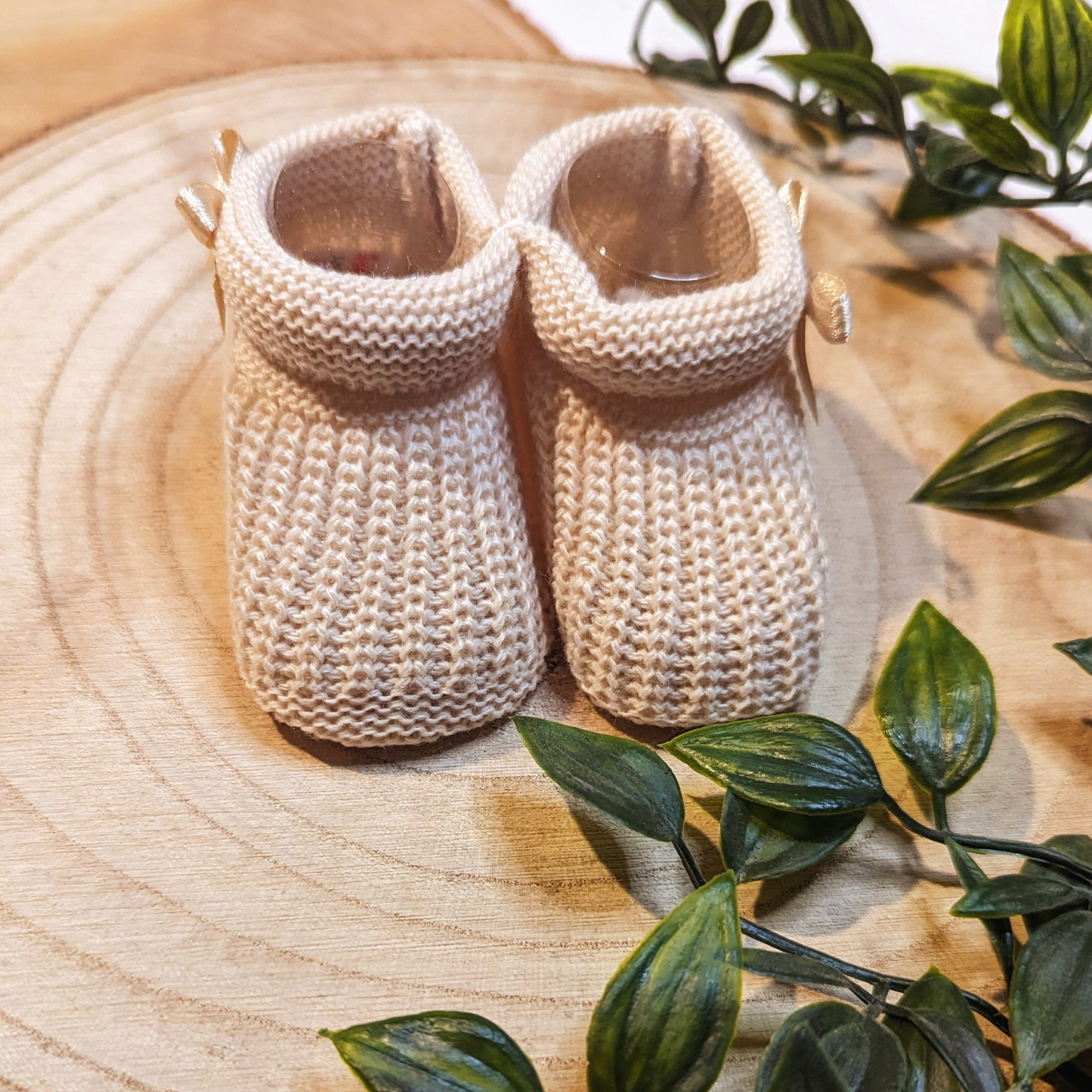 Unisex Newborn Clothes - Baby booties with a biscuit coloured knitted design, featuring a small bow on the side. (Top Angle)
